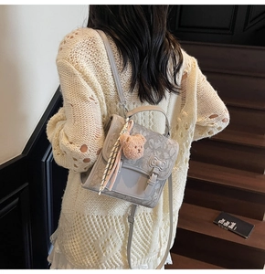 Detail of light grey retro print mini backpack with brown bear charm and ribbon scarf