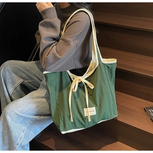 Detail of green canvas tote bag with cream trim, bow accent and Love Morning woven label