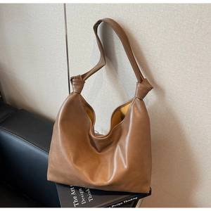 Detail shot of a brown soft leather tote bag showing double knot shoulder strap and texture