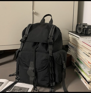 Detalle de mochila negra funcional multibolsillos con cierre de hebilla y cordón