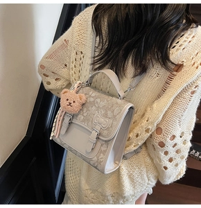 Detail of light gray backpack with butterfly floral print and cute bear plush pendant