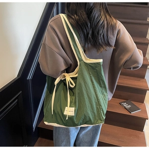 Detail of dark green tote bag with bow strap and Love Morning tag on a model