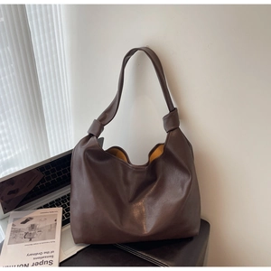 Detailed close-up of dark brown hobo bag featuring knotted strap and yellow lining details