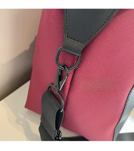 Detail of high-quality black metal D-ring and swivel hook on red fabric travel bag