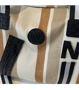Close-up of striped canvas yoga tote with textured weave and black decorative M patch