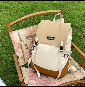 Detail of color-block nylon backpack with khaki lid and buckle on a wooden camping chair