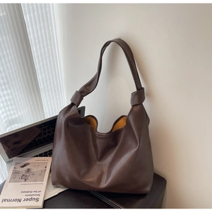 Detail of soft dark coffee PU leather tote bag featuring a decorative shoulder strap knot