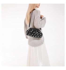 Détail du sac coque noir à rivets argentés avec texture plissée de style punk