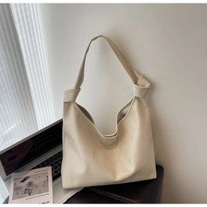 Detail of cream white leather hobo tote bag with knot strap design and laptop accessory