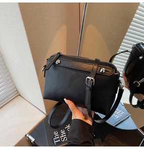 Detail einer schwarzen Lederhandtasche mit silbernen Beschlägen und verstellbarem Riemen im Alltag