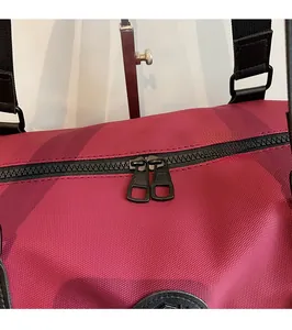 Close-up of smooth two-way black metal zippers on a burgundy outdoor travel bag