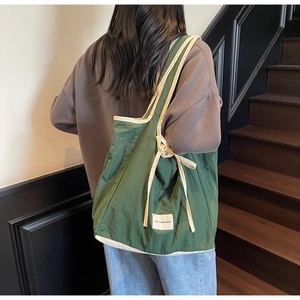 Detail of dark green tote bag with white trim and Love Morning fabric patch