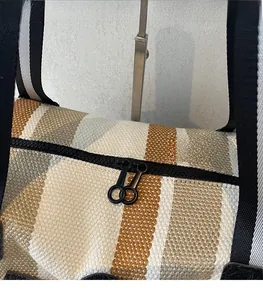 Detail of smooth metal zippers and woven fabric texture on a striped crossbody bag