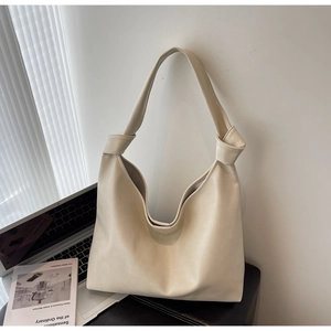 Detail of cream hobo tote bag featuring a decorative knotted shoulder strap and soft leather texture