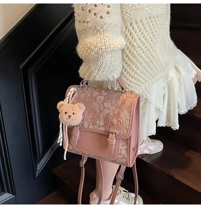 Detailed view of pink floral backpack with bow design and cute plush bear accessory