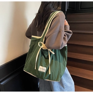 Detail of green canvas tote bag with bow tie straps and Love Morning patch on the side