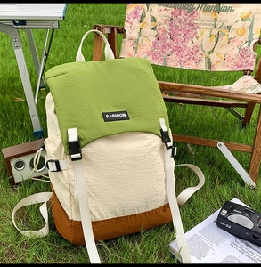 Outdoor shot of a three-color waterproof backpack with buckles on a green grass field