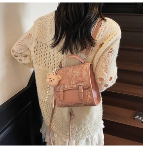 Detail of pink lace backpack with leather buckles and a cute plush bear charm