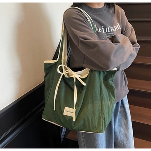 Detail of green canvas tote bag with white bow accent and Love Morning label