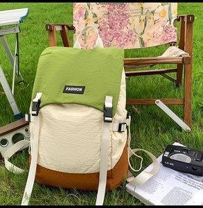 Outdoor view of water-resistant patchwork backpack on grass with camping gear