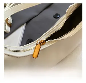 Detailed close-up of premium gold-toned zipper hardware on a white leather handbag