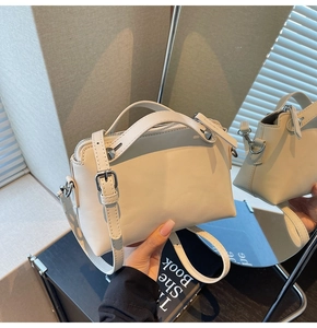 Detail der cremefarbenen Ledertasche mit Metallnieten und eleganter Spiegelreflexion