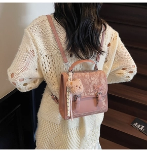 Pink jacquard backpack with plush bear charm worn by a model on wooden stairs