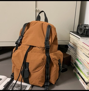 Detalle de la mochila de nailon color caramelo con cierre de hebilla y bolsillos grandes