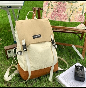 Detail of color-block water-resistant nylon backpack on chair in outdoor camping setting