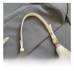Detail of cream leather shoulder bag with gold metal rings and bead pendant accessory