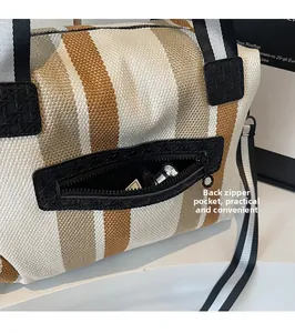 Detailed close-up of the functional back zipper pocket on a striped woven tote bag