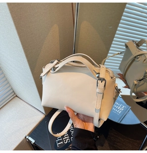 Detail der beige Boston Bag mit silbernen Kegelnieten und verstellbarem Gurt im Spiegel
