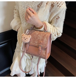 Detailed view of pink vintage backpack featuring floral texture and cute bear charm