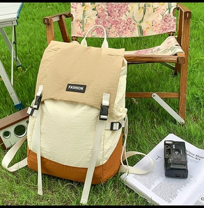 Detail of color-block water-resistant backpack on lawn with camping gear