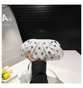 Dettaglio di una borsa bianca a pieghe con borchie argentate e tracolla sottile in pelle