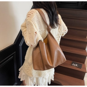 Detail of the brown leather tote bag with unique knot decoration on the shoulder strap