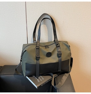 Detail of olive green travel bag with black base and adjustable strap on a dark surface