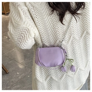 Détail d'un sac seau en cuir violet avec chaîne argentée et pendentifs tulipes