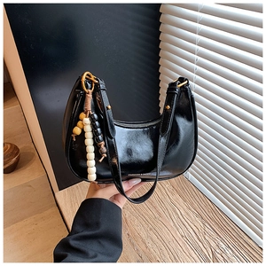 Detail of a black glossy hobo bag featuring vintage multi-color wooden beads and gold zippers