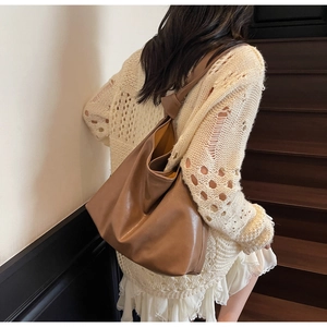 Détail d'un sac hobo en cuir marron avec bandoulière nouée porté par un mannequin