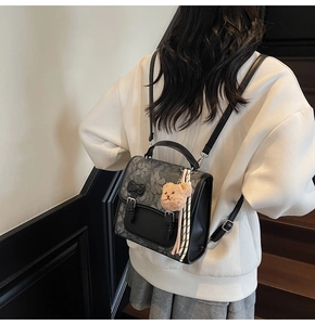 Detail of grey floral backpack with black bow and cute brown teddy bear keychain