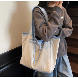 Detail view of beige canvas tote bag with sky blue shoulder straps and bow knot detail