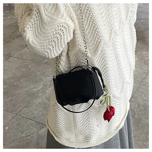 Détail du sac bandoulière en cuir noir avec chaîne argentée et pendentif tulipe