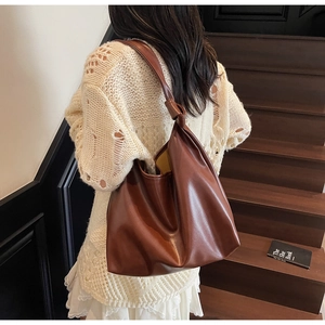 Detail view of large brown PU leather tote bag with unique knot decoration on strap