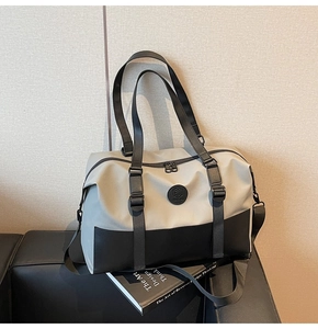 Detailed view of gray and black crossbody travel bag with buckles on a leather sofa