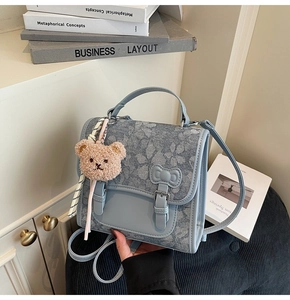 Detail of light blue floral jacquard bag with bow straps and cute brown bear pendant