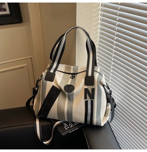 Detailed close-up of a striped canvas tote bag featuring premium leather trim and black N logo