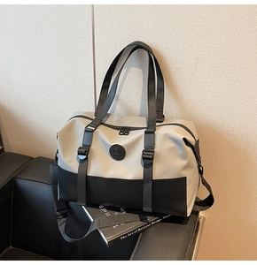Detail of large capacity duffel bag with grey-black stitching on a leather sofa