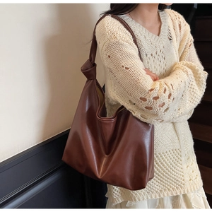 Detail showing deep brown leather tote bag with unique knot design on the strap