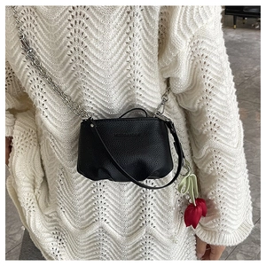 Détail d'un sac seau en cuir noir avec chaîne argentée et pendentif tulipe coloré